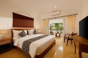 1 dormitorio con 1 cama grande y TV en Puri Tempo Doeloe Boutique Hotel, en Sanur