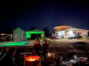 dos personas de pie junto a una piscina por la noche en Cabaña con fogon y tinaja en plena naturaleza!, en Algarrobo