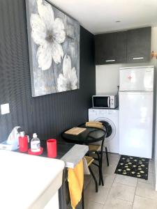 eine Küche mit einem weißen Kühlschrank und einem Tisch mit Stühlen in der Unterkunft CHAMBRE studio POMME HAPPY Aux portes de Bayeux Normandie 1 à 2 pers in Monceaux-en-Bessin