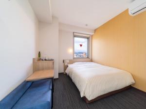 een kleine slaapkamer met een bed en een raam bij Super Hotel Yahaba Station East Exit in Yahaba