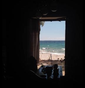 a window with a view of the beach and the ocean at All weather house in Elíka