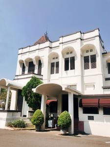 um edifício branco com dois arbustos à frente em Hotel Candi Baru em Jomblang