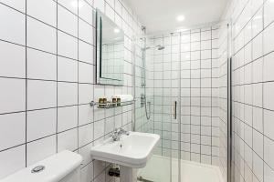 a white tiled bathroom with a sink and a shower at Idyllic Islington Flat in London
