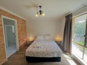 a bedroom with a bed with two lamps and two windows at Emily St Escape in Esperance
