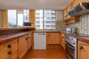 cocina con armarios de madera y lavavajillas blanco en Sandbar Unit 203, en Forster