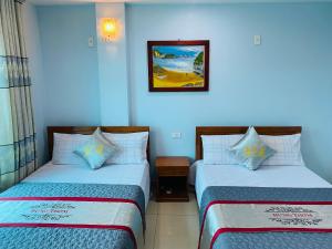 a room with two beds and a picture on the wall at Nhà nghỉ Hưng Thơm in Cat Ba