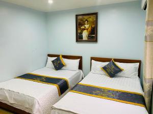 two beds in a room with a picture on the wall at Nhà nghỉ Hưng Thơm in Cat Ba