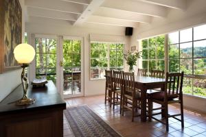 a dining room with a table and chairs and windows at Lake Cottage in Daylesford