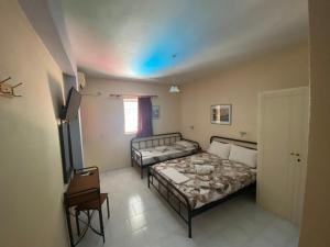 a small room with two beds and a chair at Polyxenis Rooms in Lygia