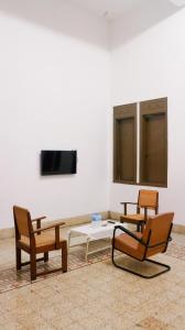 a room with three chairs and a table and a tv at Hotel Candi Baru in Jomblang