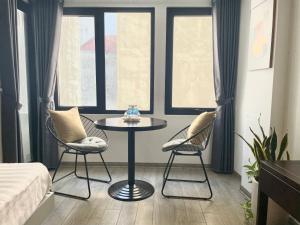 - une petite table et deux chaises dans une chambre avec fenêtres dans l'établissement Kem Apart 01, à Hanoï