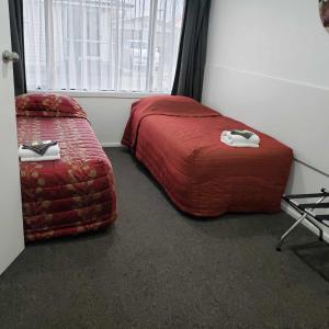 a bedroom with a red bed and a chair at Brown Trout Motel in Pahiatua
