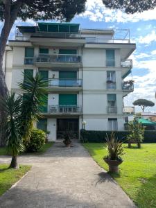 um edifício alto e branco com árvores em frente em Colibrì, vicino a pineta e mare em Viareggio