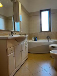 ein Badezimmer mit zwei Waschbecken, einer Badewanne und einem WC in der Unterkunft A 5 MINUTI DA TRAPANI e FREE PARKING in Torre Nubia