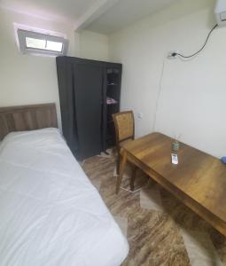 een slaapkamer met een bed en een houten tafel bij Green Palma in Koetaisi