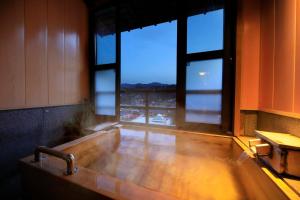 y baño con bañera y ventana grande. en 日長庵 桂月 en Hirugami