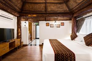 Vijayshree Resort, Hampi في هامبي: غرفة نوم بسرير وتلفزيون بشاشة مسطحة
