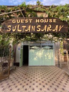 a guest house entrance with a sign over a garage at Sultan Sarai Osh in Osh