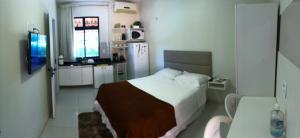 Un pequeño dormitorio con una cama y una cocina. en Apartamento Villa do Porto, a 300 metros do Beach Park, en Aquiraz