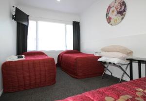 a bedroom with two red ottomans and a window at Brown Trout Motel in Pahiatua