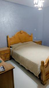 een slaapkamer met een houten bed en een bureau bij شقة مجهزة بالكامل in Saidia 