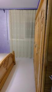 een slaapkamer met een houten bed en een raam bij شقة مجهزة بالكامل in Saidia 