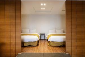 two beds in a small room with wooden floors at Olle Resort & SPA in Jeju