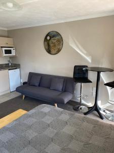 a living room with a blue couch and a clock on the wall at Riverside Studio in Wanaka