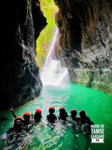 a group of people in the water in front of a waterfall at House of TamSe Laagans ' Inn in Badian