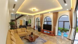 een woonkamer met een bank en een tv bij The Oxford Villa at Venus by Flamingo Dai Lai Resort in Phúc Yên