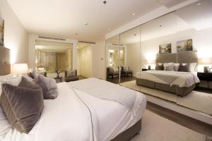 een slaapkamer met een groot wit bed en een spiegel bij SHH - D1 Tower Apartments in Dubai