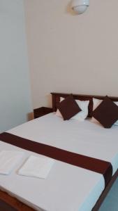 uma cama branca com almofadas pretas num quarto em MercuryFM 103 Guest House - Colombo 3 em Colombo