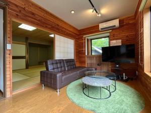 a living room with a leather couch and a table at FOREST HOUSE in Kusatsu