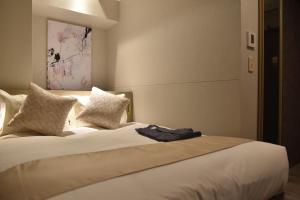 1 dormitorio con 1 cama grande con sábanas y almohadas blancas en Hotel Cordia Osaka Hommachi, en Osaka