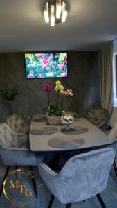 mesa de comedor con sillas y TV en la pared en Montagnoli Luxury Villa en Cluj-Napoca