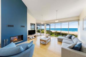 a living room with two couches and a fireplace and the ocean at Chocolate Gannets in Apollo Bay