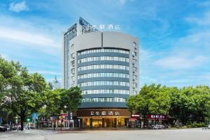 a tall white building with trees in front of it at Xinhuating Business Hotel in Lishui