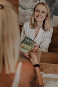 a woman is holding a book in her hand at Sporthotel Kitz in Bruck an der Großglocknerstraße