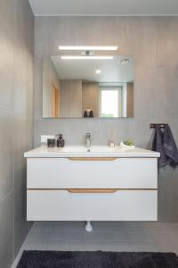 La salle de bains est pourvue d'un lavabo blanc et d'un miroir. dans l'établissement Old town luxury penthouse apartment with Emajõgi view, à Tartu