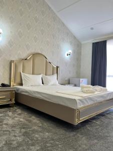 a bedroom with a large bed with a large headboard at Oqshom Plaza Hotel in Qarshi