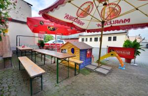 a playground with benches and a play house and an umbrella at Hotel Isora in Ostrava