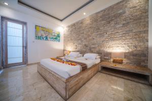 a bedroom with a large bed and a brick wall at Shakti Villa Umalas in Canggu