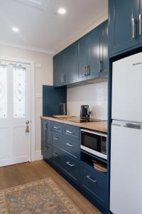 kuchnia z niebieskimi szafkami i białą lodówką w obiekcie Mount Booralee w mieście Blackheath