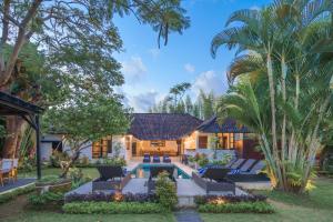 スミニャックにあるAryana Estate by Villas Direct Baliのヤシの木とスイミングプールのある家