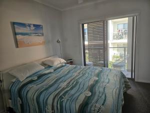 ein Schlafzimmer mit einem Bett und einem großen Fenster in der Unterkunft Caves Beach Terrace in Caves Beach