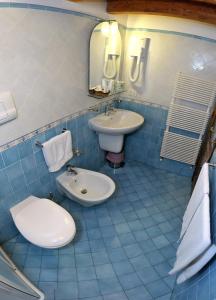 Baño de azulejos azules con aseo y lavamanos en Solemar Hotel en Leni