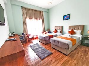 1 dormitorio con 2 camas, escritorio y TV en Tshongdu Boutique, en Paro