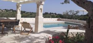 a patio with a table and chairs next to a swimming pool at Holiday Home Cosimo in Locorotondo