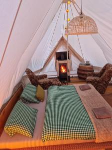 a tent with a bed and a fireplace in it at Glamping Štôla- Symbioza in Štôla