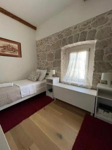 1 dormitorio con pared de piedra, cama y ventana en Villa Luca, en Grude